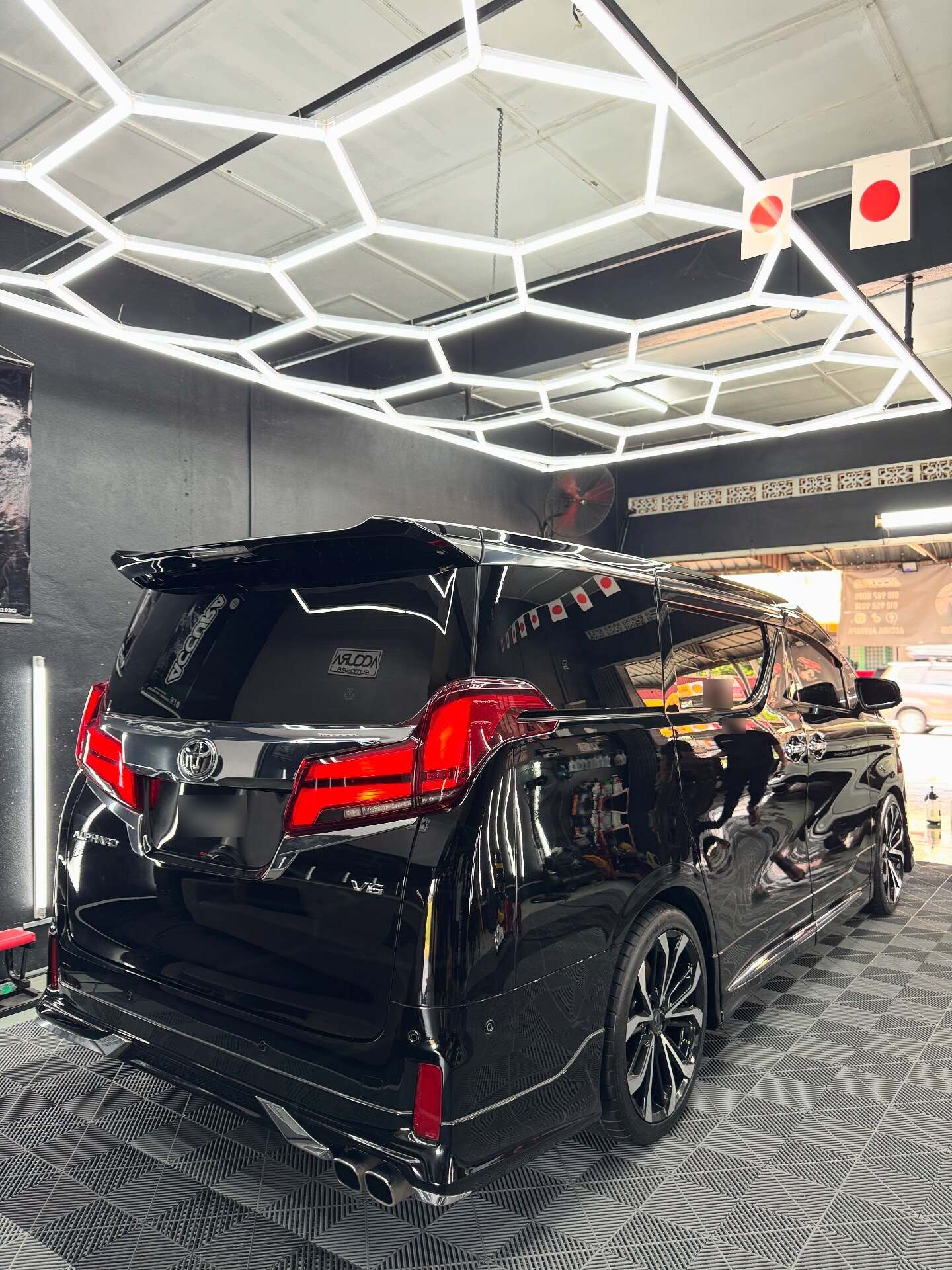 Toyota Alphard hitam dilihat dari belakang di dalam studio Accura